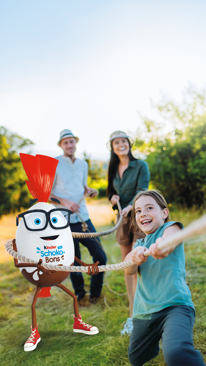 Mr. Bon steht gemeinsam mit einer Familie in der Natur - zusammen spielen sie Tauziehen