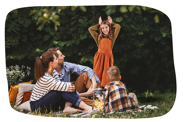 Eine Familie macht ein Picknick in der Natur. Die Eltern sind mit ihrem Sohn und ihrer Tochter da. Alle zusammen spielen Pantomime.