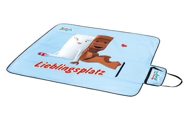 Picknick Decke mit einem Motiv von Milky und Schoki der Marke kinder Riegel und als Schriftzug 'Lieblingsplatz'